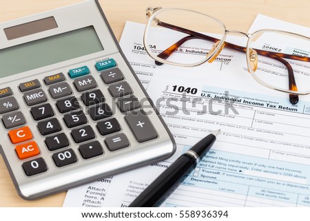 Tax form with pen, glasses, and calculator