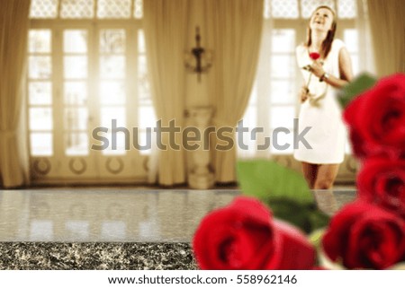 wooden desk of free space for your decoration and woman with one rose flower in hands with few blurred red roses 