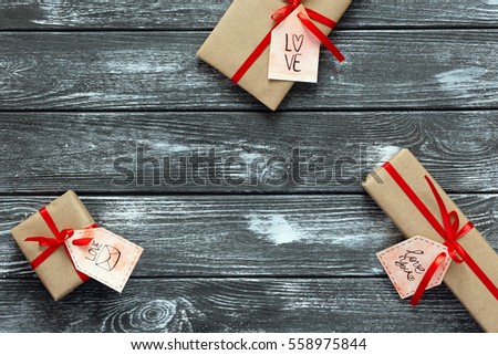 Valentines Day Concept wrapped in beige Color Paper and tied up with red Ribbon Gift Boxes of different Size and Shape on Vintage rough grey Wood Texture Background flat Lay top View with Cards