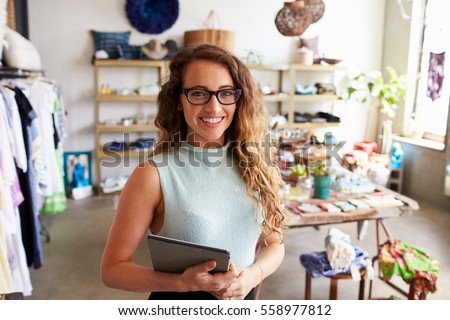 Female business owner holding tablet computer in clothes shop Royalty-Free Stock Photo #558977812