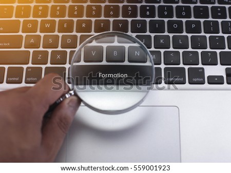 Formation button on a keyboard with hand holding a magnifying glass