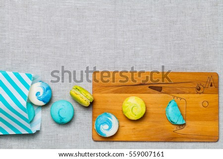 Top view of macarons of different colors on the wooden board with a picture of a fox. Copy space.