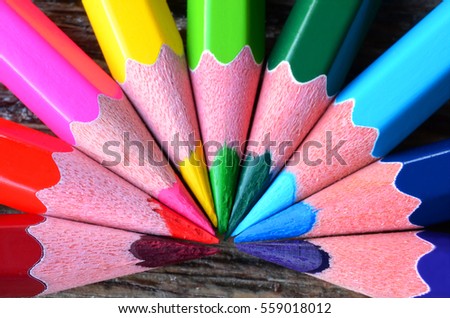 A top view image of brightly coloured pencil crayons in a rainbow pattern. 