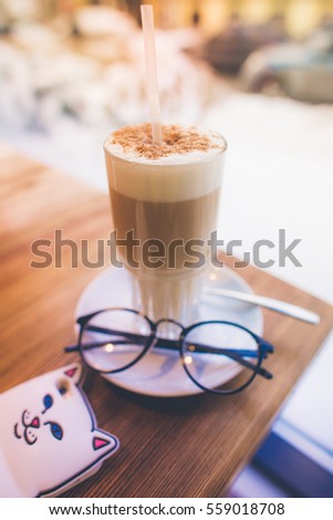 coffee latte cappuccino on the wooden table near the winter window with colorful background with spoon and glasses 
