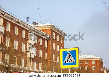 Red residential house in a residential area. Walking area. Winter landscape. Open space. Contemporary Russia. Signpost. Crosswalk.