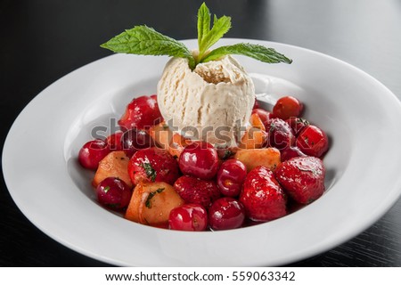 juicy caramelized fruit flambe with ice cream. Strawberry, cherry, apple, pear decorated with mint sprig