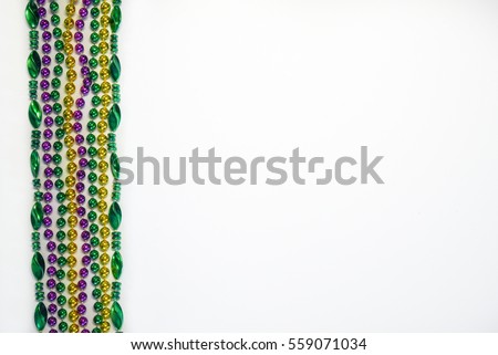 Mardi Gras beads, masks and banner reading  Mardi Gras in traditional festive colors on a white background in horizontal or landscape format with lots of copy space