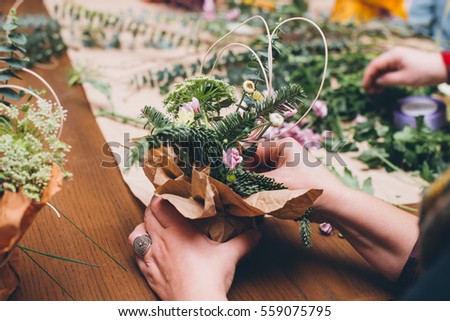 Woman's hands making flower composition at floristic workshop, DIY tools, branches. stems and twine for creative work