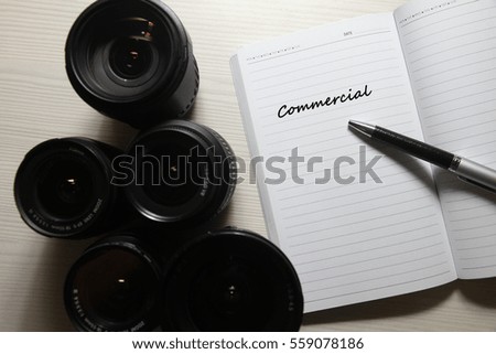 Note with pen, camera lens and text Commercial.