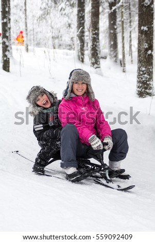Mother with baby in winter wood snow-cats ride