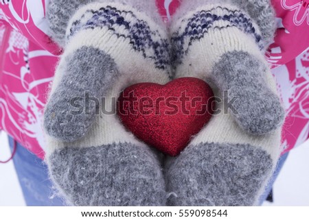 Heart in the girl's hands. Young woman holding heart mittens in winter