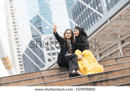 Business woman taking picture with young muslim girl by using mobile phone. Technology and lifestyle concept, taking own photo by using mobile phone or selfie is very popular in present.