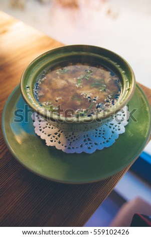 Tasty miso soup in plate on wooden table near winter window
