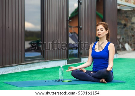 young girl is preparing for a training session. yoga mat and water bottle.
lotus posture
