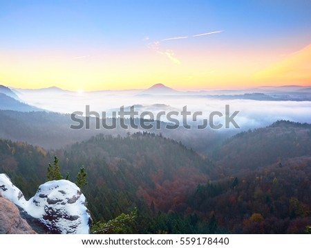 Red filter photo. Red daybreak. Misty daybreak in a beautiful hills. Peaks of hills are sticking out from foggy background, the fog is red and orange