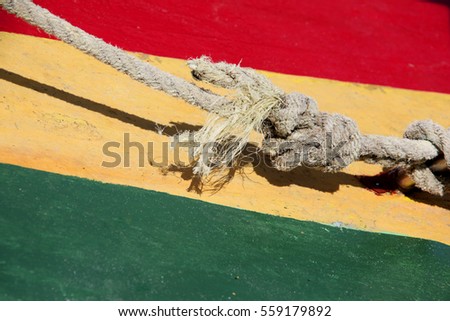 Typical Rastafarian Caribbean colors of red, green & yellow, painted on wood, with a nautical knot in front, St George, Grenada.