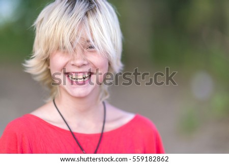 Portrait of blonde girl in a red blouse with a smile at sunny day