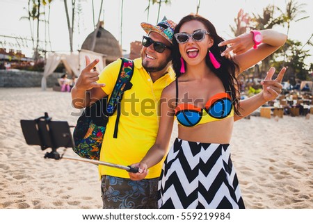 young beautiful hipster couple in love on tropical beach, taking selfie photo on smartphone, sunglasses, stylish outfit, summer vacation, having fun, smiling, happy, colorful, positive emotion