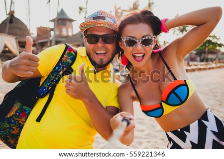 young beautiful hipster couple in love on tropical beach, taking selfie photo, sunglasses, stylish outfit, summer vacation, having fun, smiling, happy, colorful, positive emotion