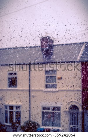 Stormy weather at town. Blurred houses seen through a window with water droplets on it. Levenshulme Manchester England