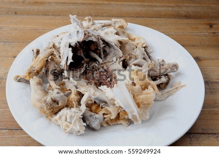 Roast chicken carcass remains on a plate on a wooden table