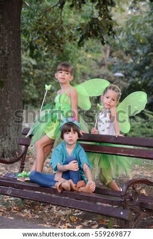 Boy and two girls in a green fairy costume with wings in the park. Kids in the park