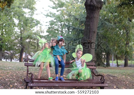 Boy and two girls in a green fairy costume with wings in the park. Kids in the park