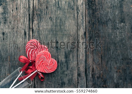 Heart shaped lollipop in the glass on background wooden. (Old color tone image)