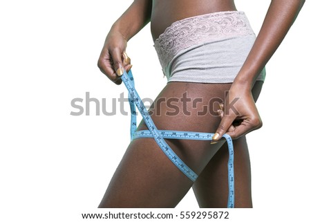 black girl is measuring her thigh with a metric tape measure