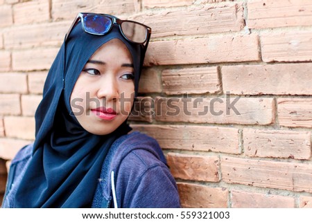 Muslim woman post on brick wall 