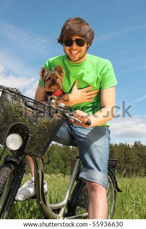 Young beautiful man riding a bike with his small yorkshire terrier