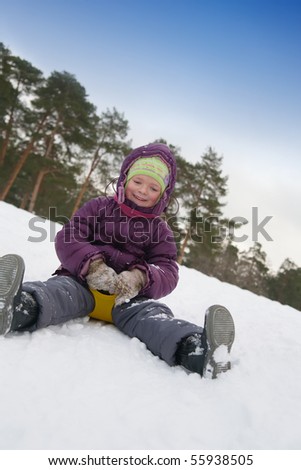  Young girl riding in a city park with a snow slide.