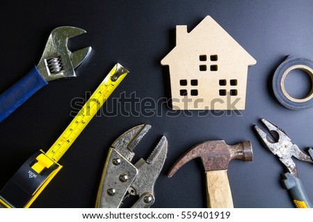 Wooden house toy and construction tools on black background with copy space.Real estate concept, New house concept, Finance loan business concept, Repair maintenance concept Royalty-Free Stock Photo #559401919
