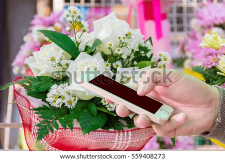 On Valentines Day. Man use mobile phone, beautiful flowers as background 