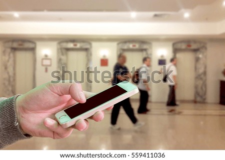 Man use mobile phone, blur image of elevator hall as background.