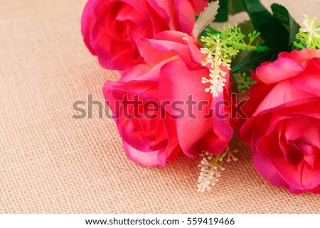 Red fabric roses on canvas background, closeup picture.