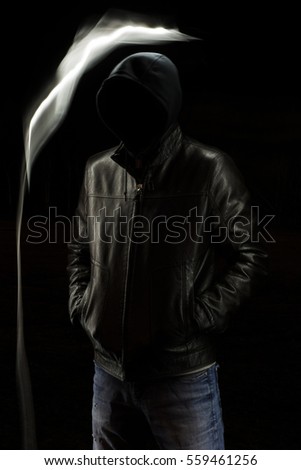 Mystic black hooded man standing in the darkness. Evil spirit.