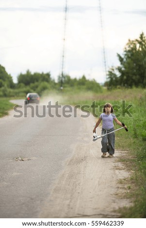 girl child riding  scooter on  road near car  In  countryside, the concept of child safety, childhood