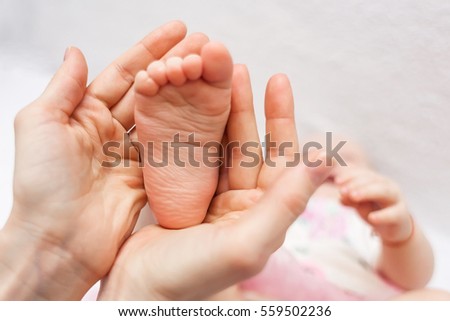 Mother holding her baby daughter's feet in her hands.