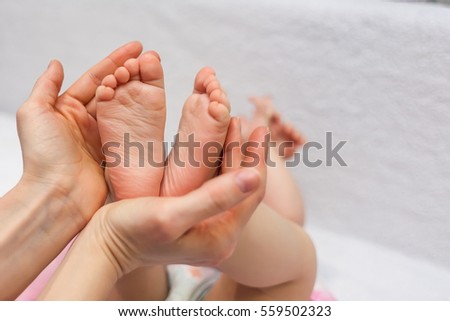 Mother holding her baby daughter's feet in her hands.