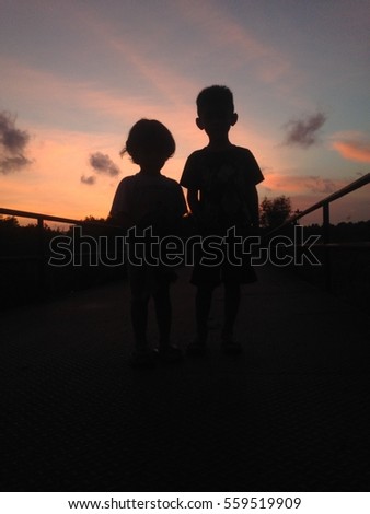Silhouette picture of boy and girl during  majestic sunset with red sky
