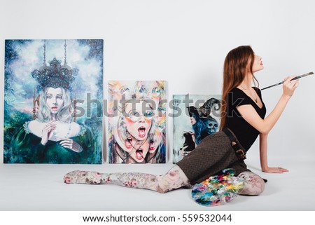 Beautiful female artist at Picture canvas on white background. Girl painter with brushes and palette. Art creation concept. sitting on the floor against the backdrop of real paintings.