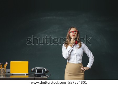 Thoughtful businesswoman on blank chalkboard background.