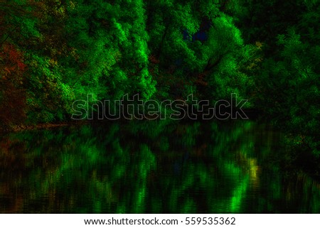 Scenic autumn colors, green trees reflecting on the water of a river (Nidda Frankfurt am Main), seasonal fall landscape,water reflections,surreal fantasy,peaceful,quiet,nature