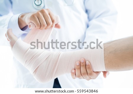 Close-up of male doctor bandaging foot of patient at doctor's office. Royalty-Free Stock Photo #559543846