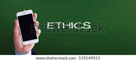 Smart phone in hand front of blackboard and written ETHICS
