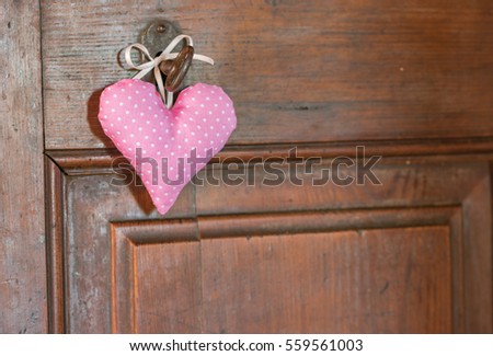 Cute little pink heart hanging on an key of a wooden door, romantic love background with copy space.