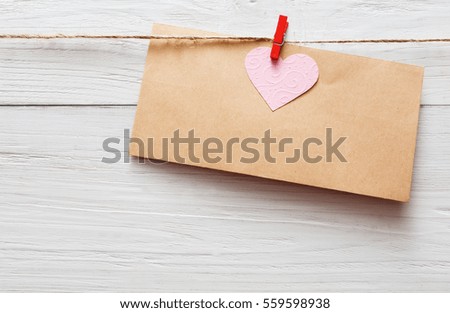 Valentine background, empty craft paper greeting card on clothespin on white rustic wood planks. Happy lovers day card mockup, copy space