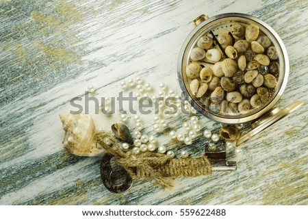 Scattered pearl beads and converted clock with seashells and old key on the old whiteboard.