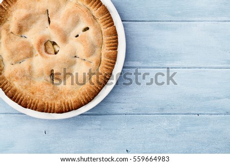 Homemade apple pie dessert shot from overhead over a blue rustic wooden table top with room for copy space.